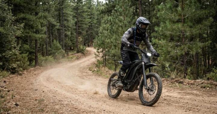 Electric dirt bike riding on a rugged off road forest trail