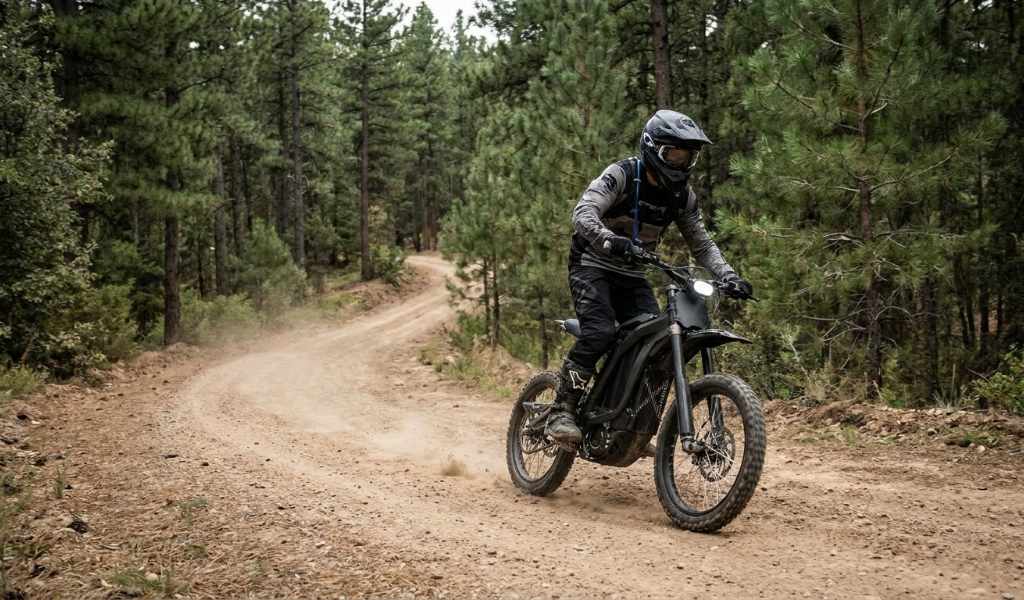 Electric dirt bike riding on a rugged off road forest trail
