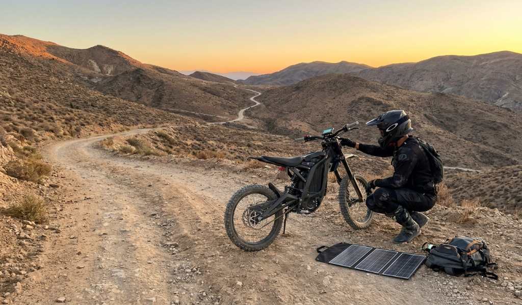 Rider checking electric dirt bike battery level before a trail ride