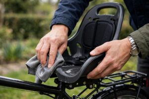Parent wiping down a baby bike seat shell with a damp cloth